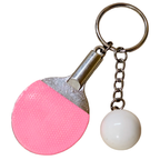 A close-up of pink ping-pong paddle keychain charm and a white ball accessory hanging from a gold-tone ring, in the white background.