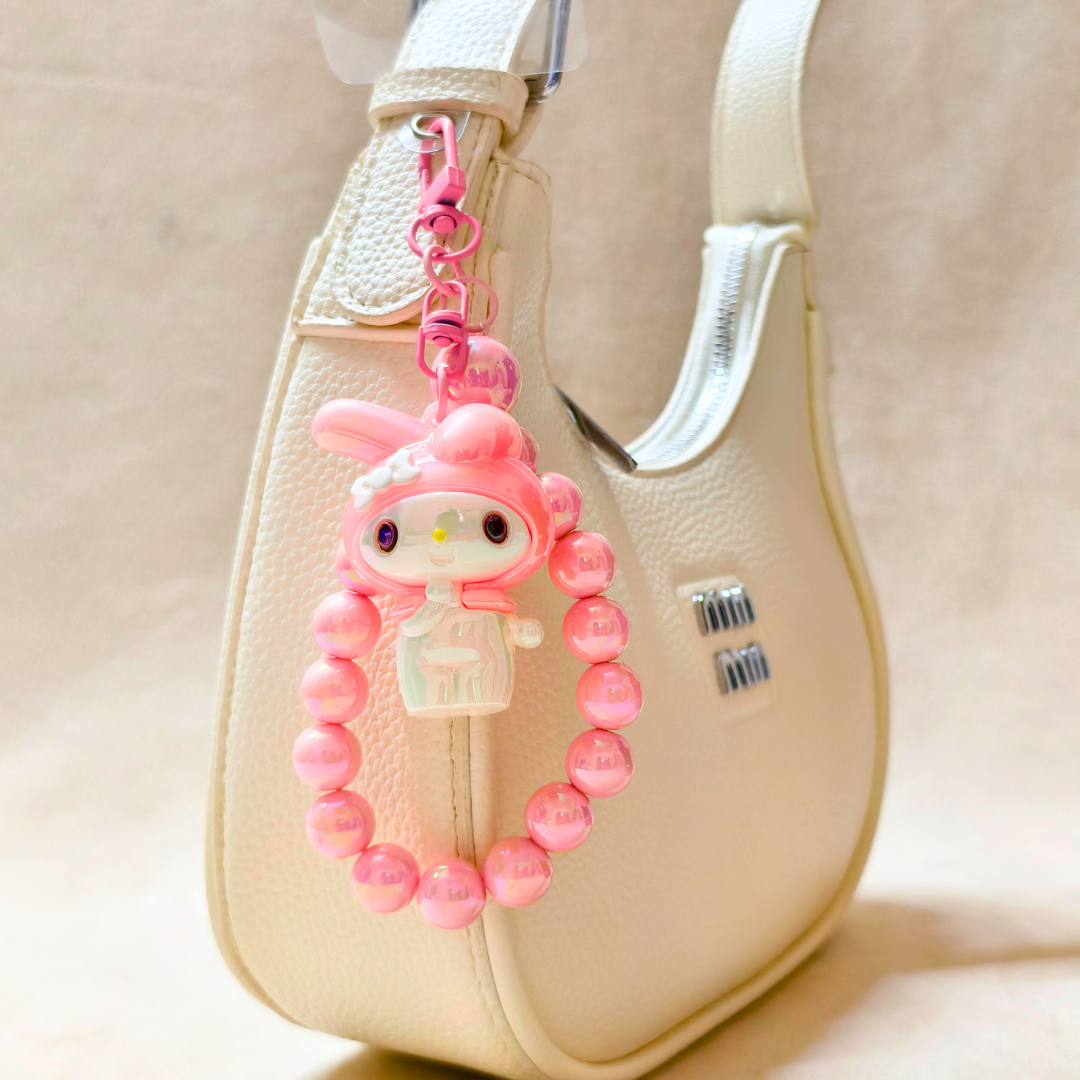 Pink character keychain with beads on a beige bag