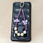Phone case with a decorative keychain featuring purple flowers and pearls on a beige background