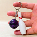 Sporty Bowling Keychain along with Silver chain and ring with Ball hold in hand  on Beige Background.