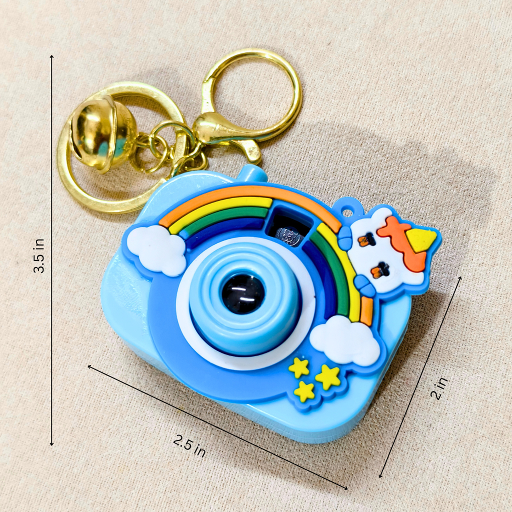A blue cartoon camera-shaped keychain with a gold clasp, shown on a beige fabric background with dimension lines indicating 3.5 in height, 2.