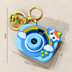 A blue cartoon camera-shaped keychain with a gold clasp, shown on a beige fabric background with dimension lines indicating 3.5 in height, 2.