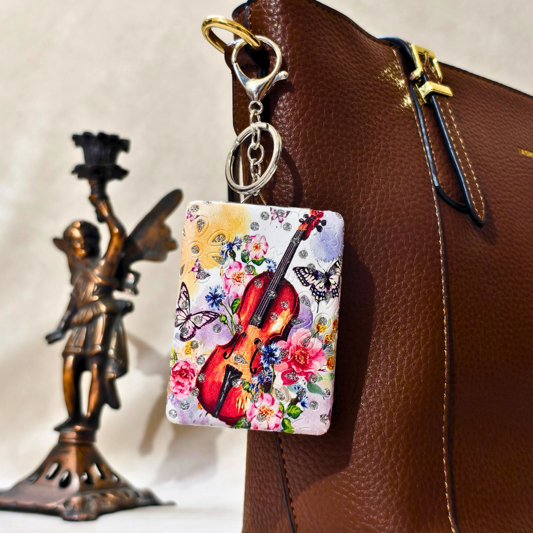 Colorful keychain with floral and butterfly design attached to a brown leather bag.