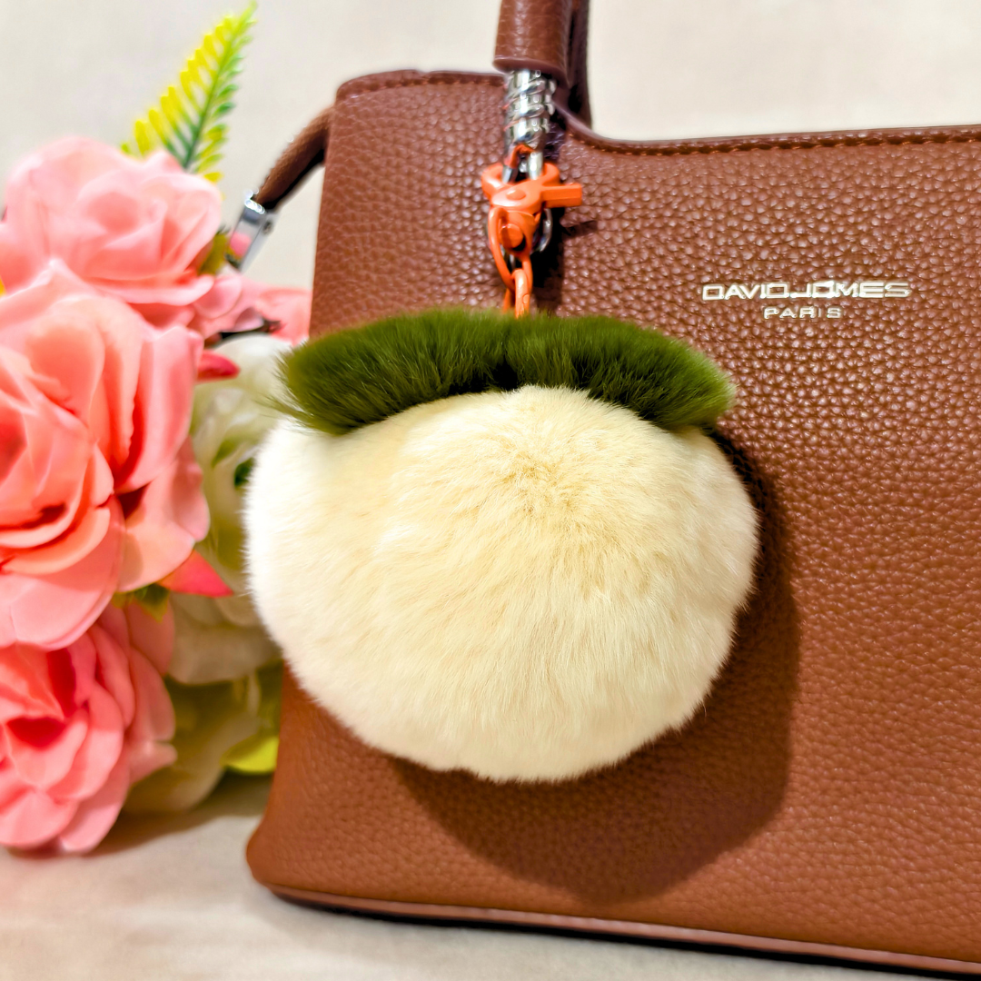 White Key Chain Displayed On Bag In Front Of Beige Background