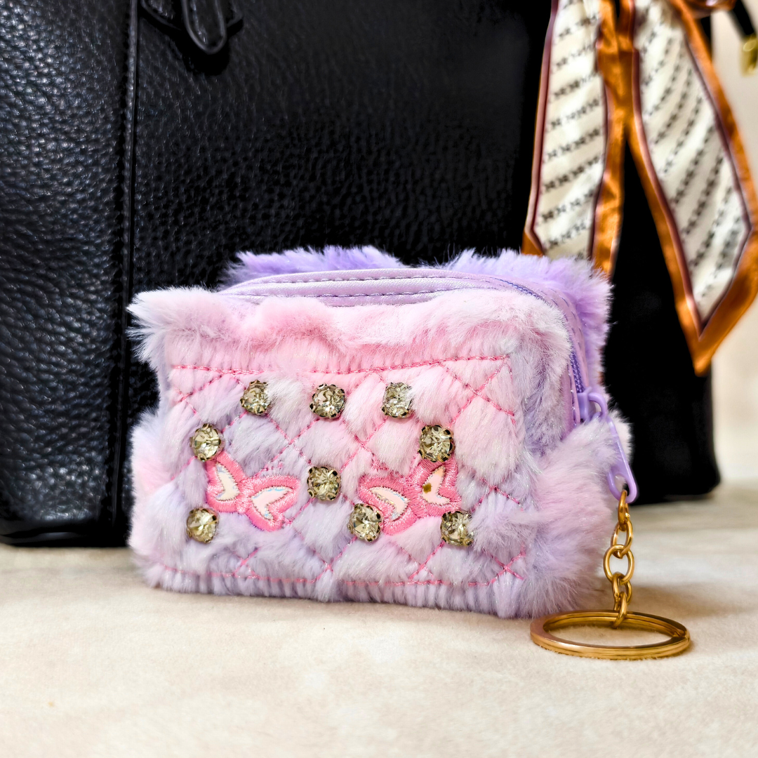 Pink textured pouch with decorative elements and a keychain on a surface.