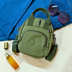 Green bag with sunglasses and a bottle on a blue fabric background