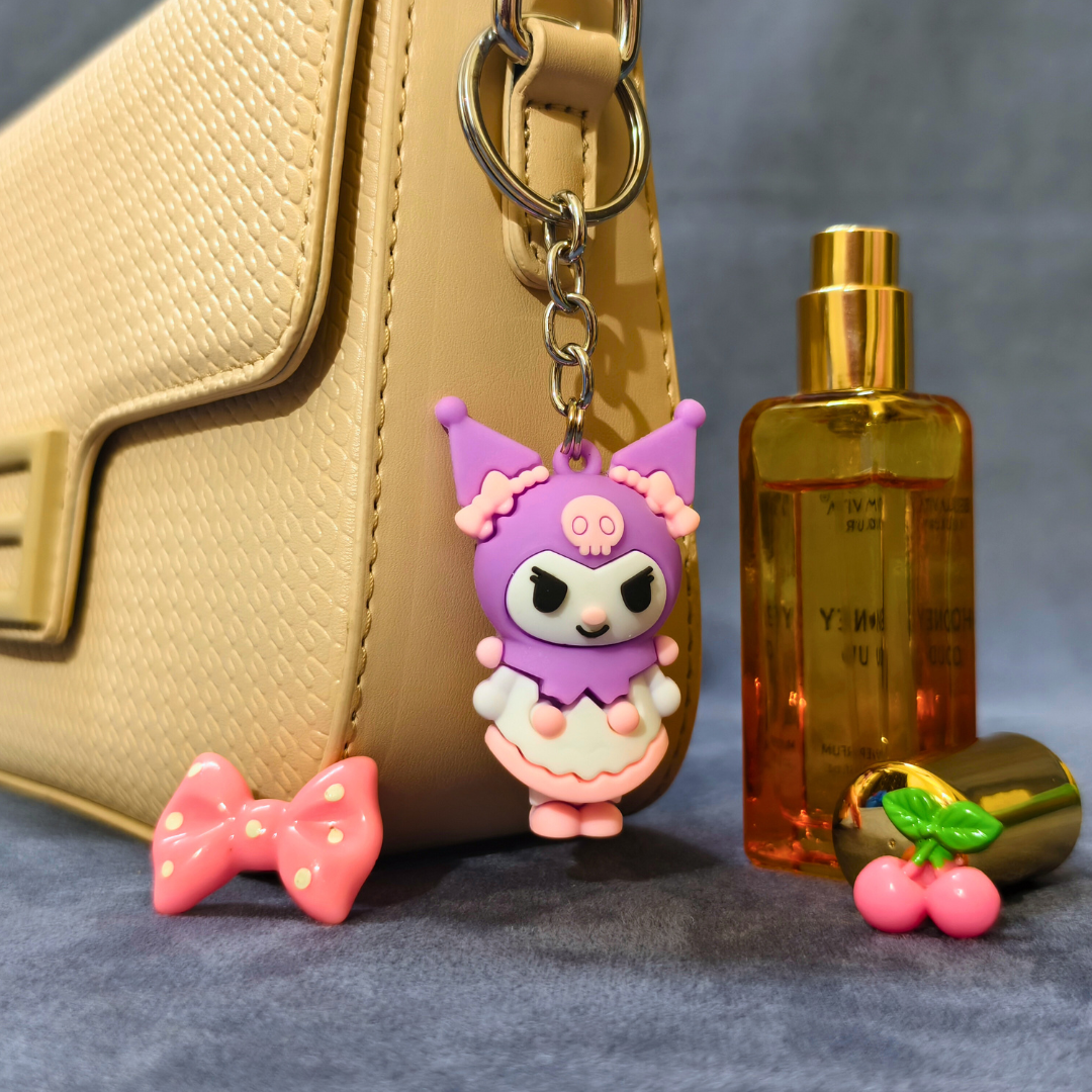Pink and purple character keychain with a gold handbag and bottle in the background