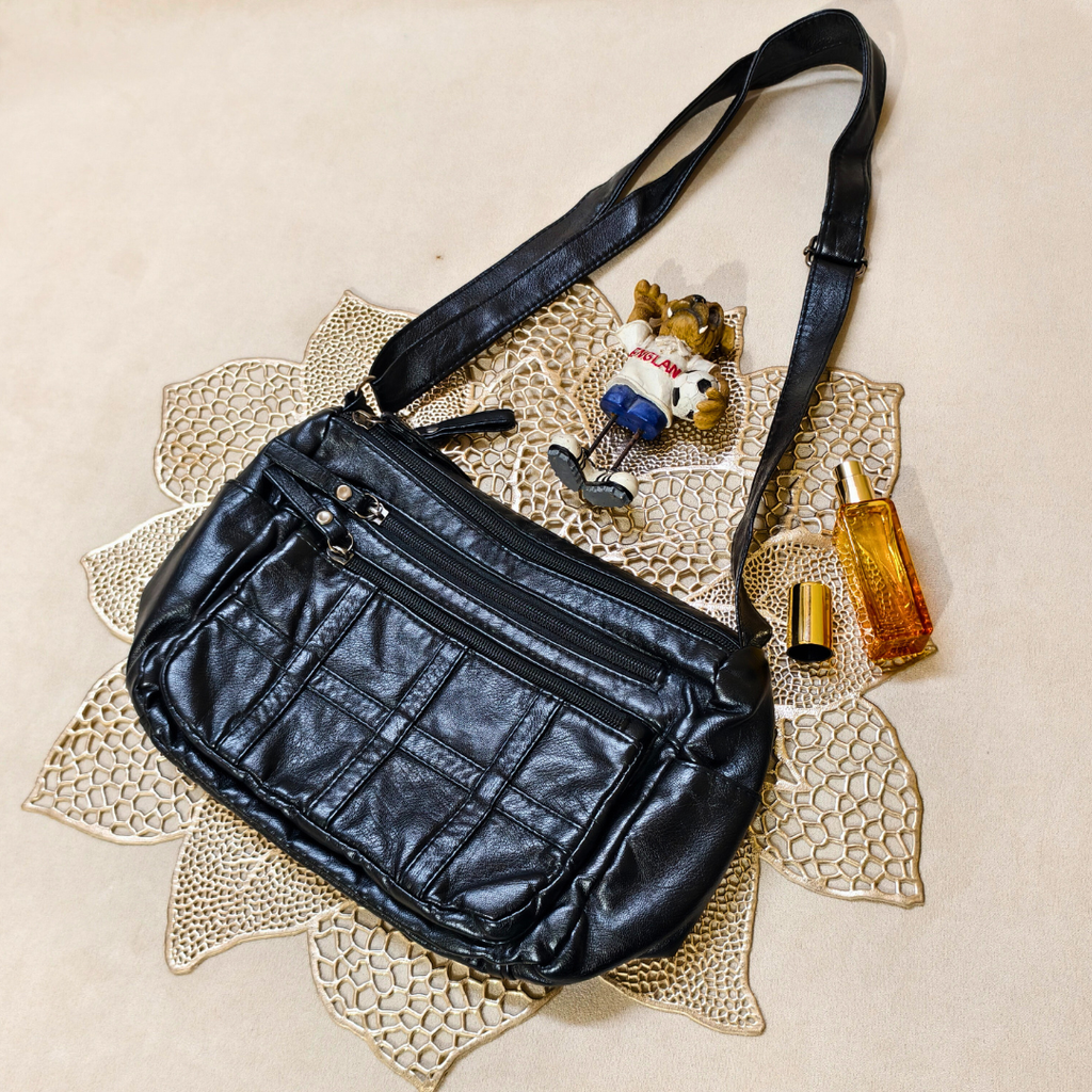 Black leather bag on a textured surface with small items around