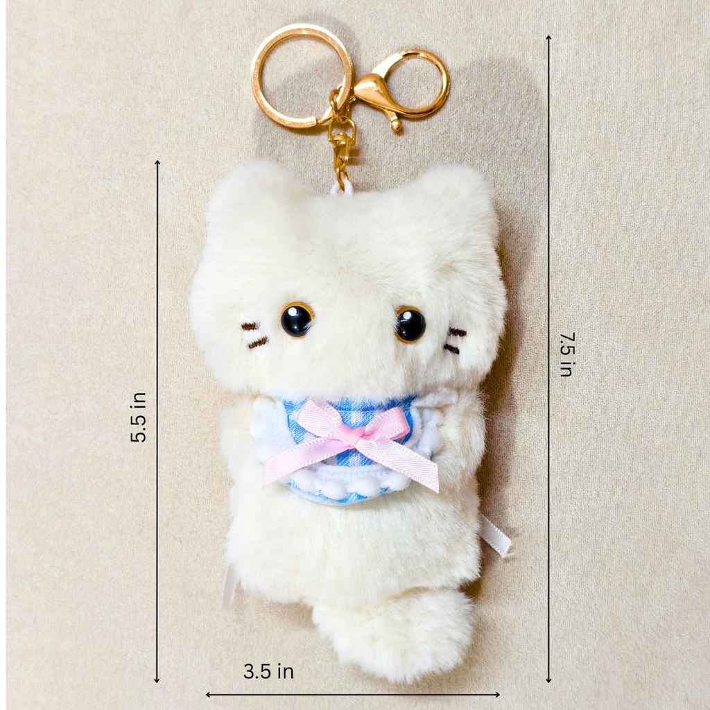 A white plush cat keychain with a gold clasp, black eyes, and a pink and blue bow, shown on a beige background with dimension lines indicating 5.5 in height, 7.