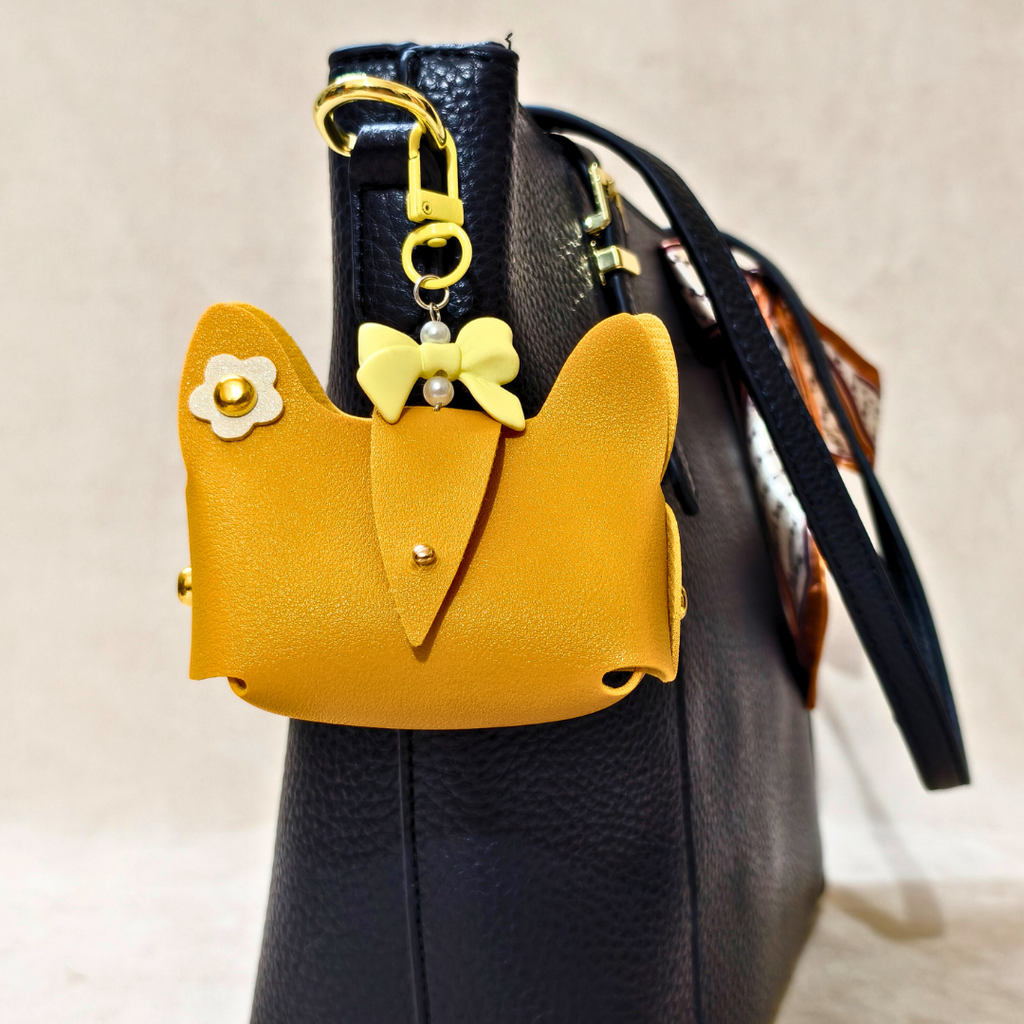 Black handbag with a yellow heart-shaped pouch featuring a bow and flower detail.