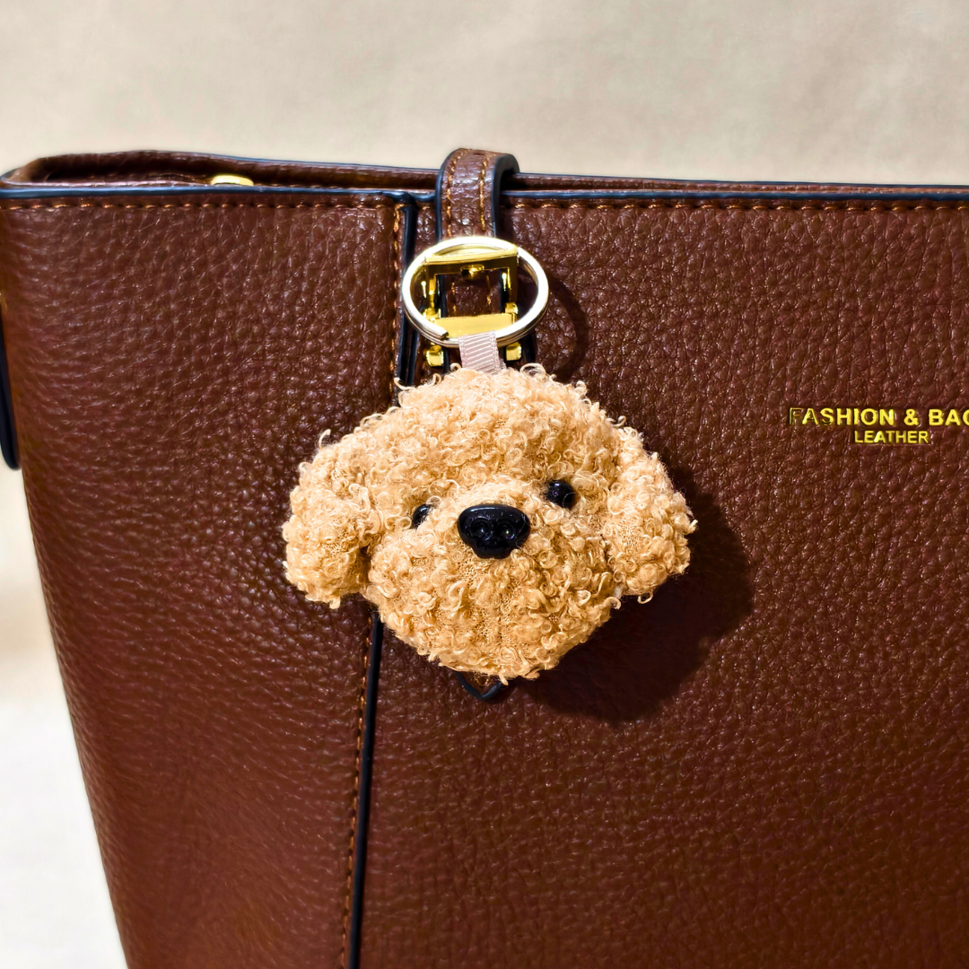 Brown teddy bear-shaped keychain attached to a brown leather bag.