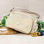 Cream Ivory Sling Bag With Props In Front Of Beige Background.
