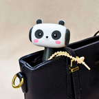 Panda-shaped phone holder inside a black handbag on a beige background