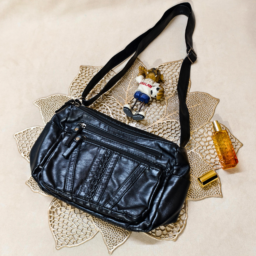 Black leather bag with a small toy and bottle on a decorative mat