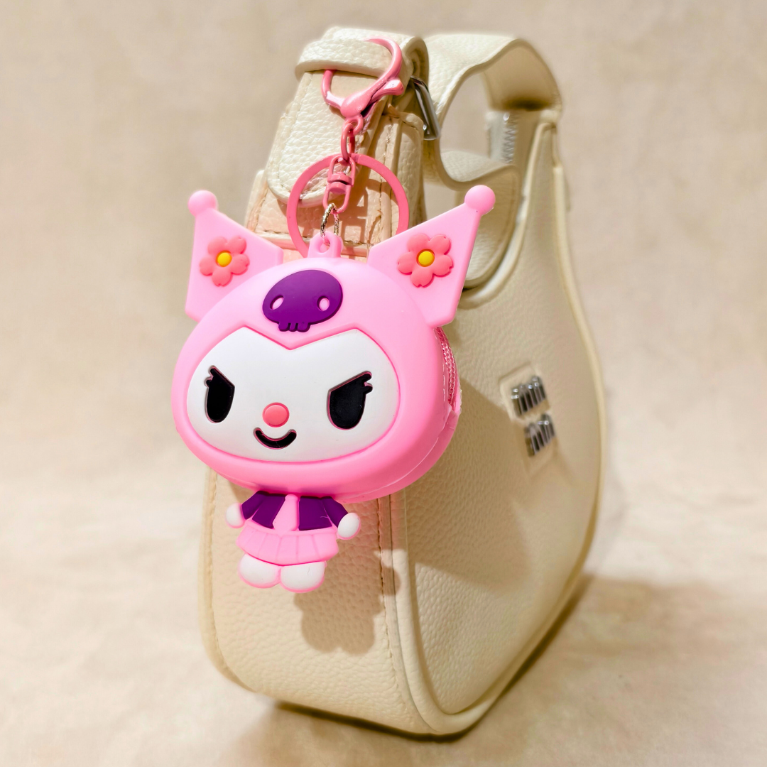 Pink cartoon character keychain attached to a beige handbag.