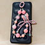Phone case with a decorative pink butterfly charm on a beige background