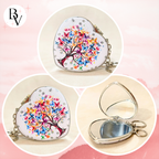 Heart-shaped silver compact mirror with a colorful butterfly tree design, shown closed and open on a soft pink background.