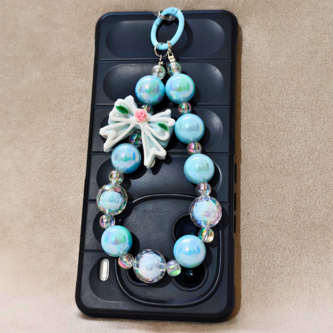 Phone case with decorative beads and a flower charm on a beige background