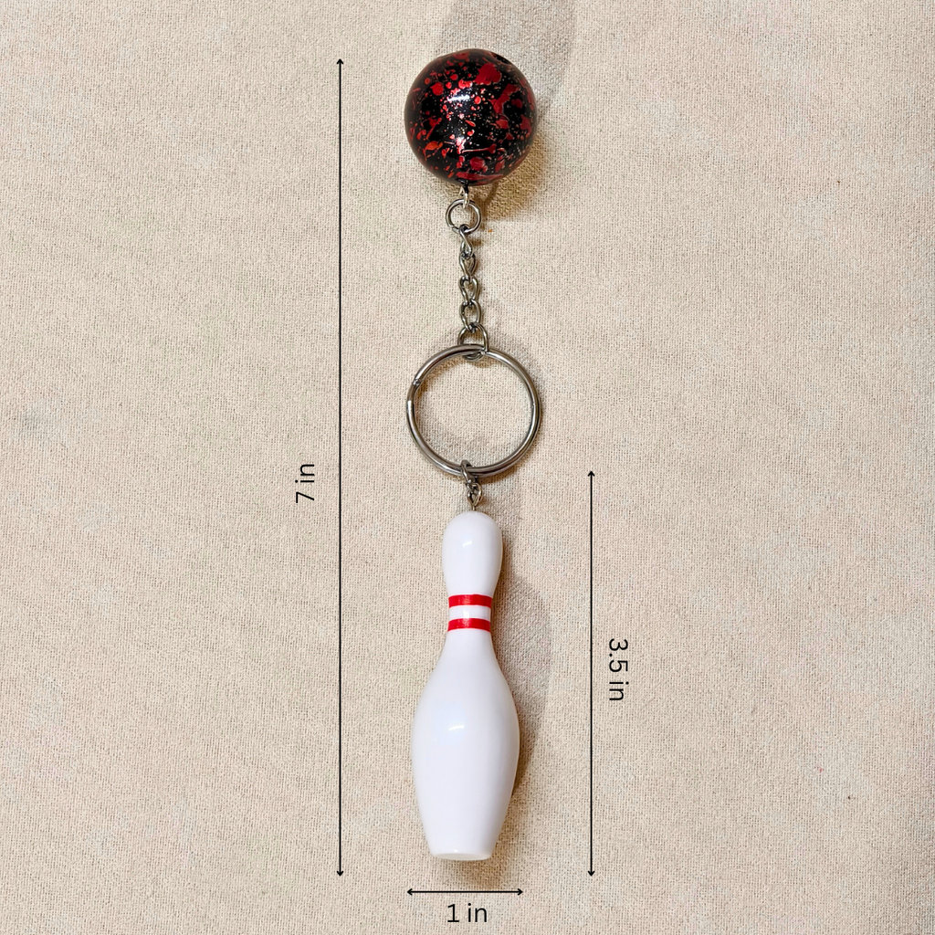 A bowling pin keychain shown on a beige textured background with dimension lines and labels indicating a height of 7 inches, pin height of 3.5 inches, and pin width of 1 inch.