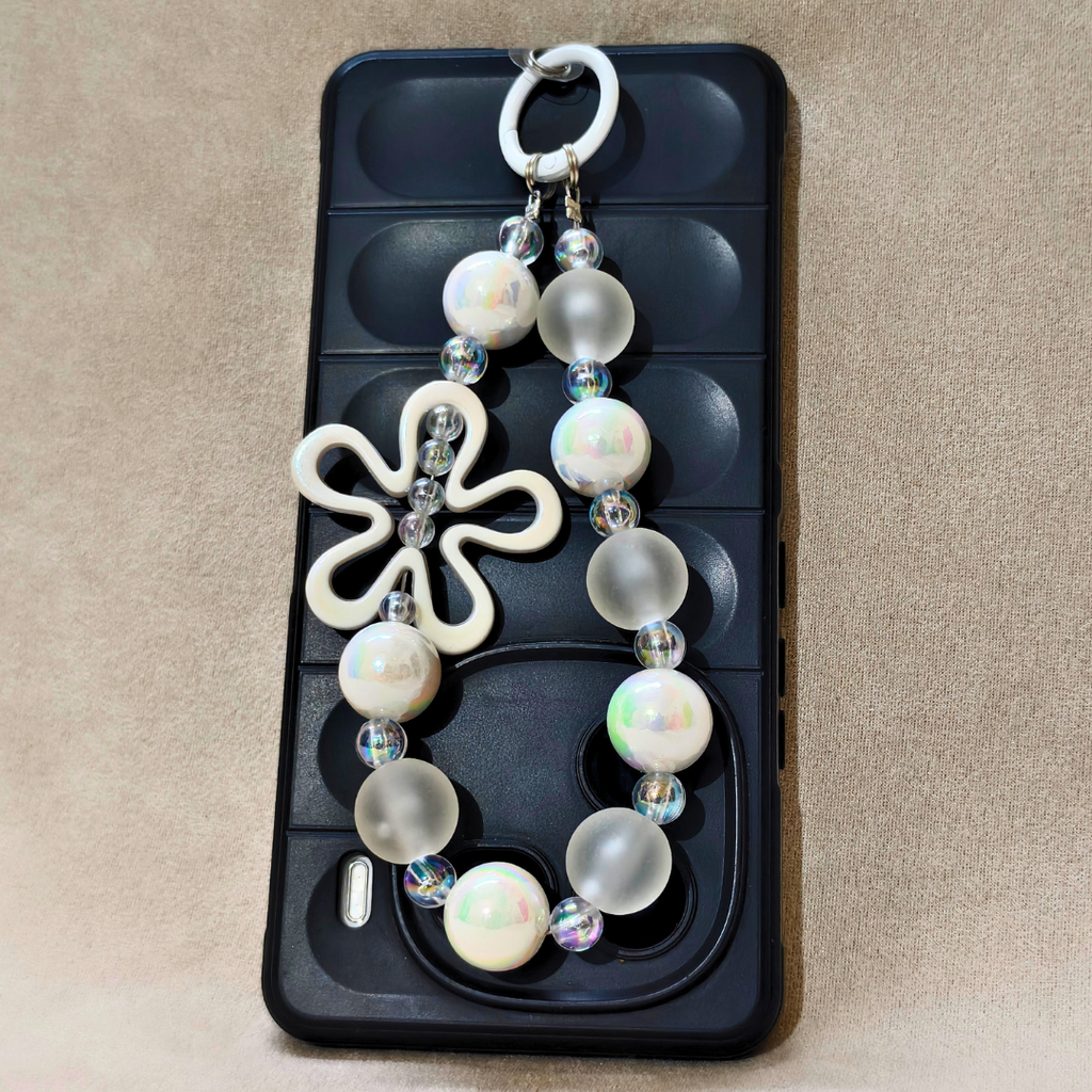 Decorative keychain with beads and a butterfly charm on a phone case.