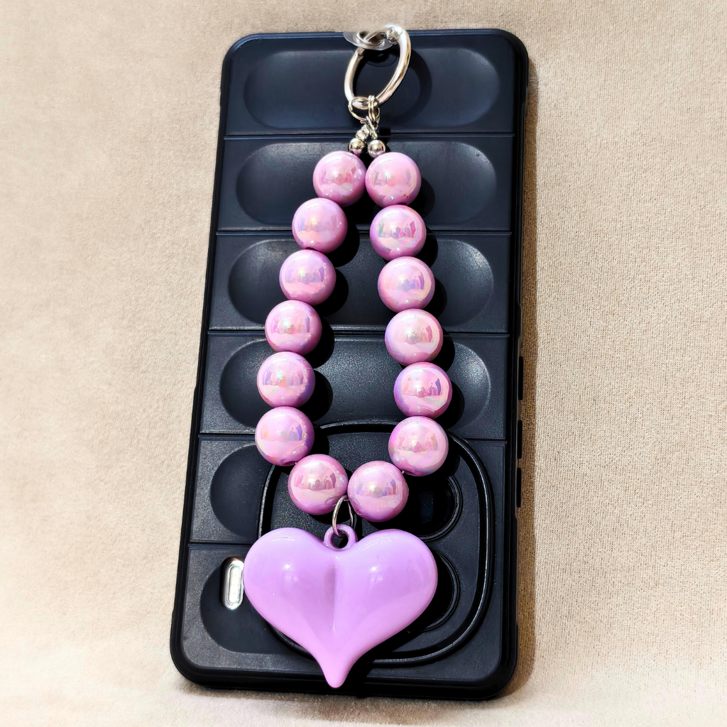 Pink beaded keychain with a heart charm on a black phone case.