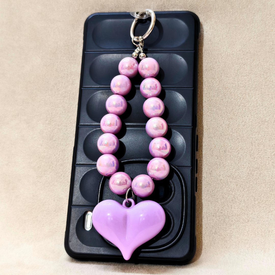 Pink beaded keychain with a heart charm on a black phone case.