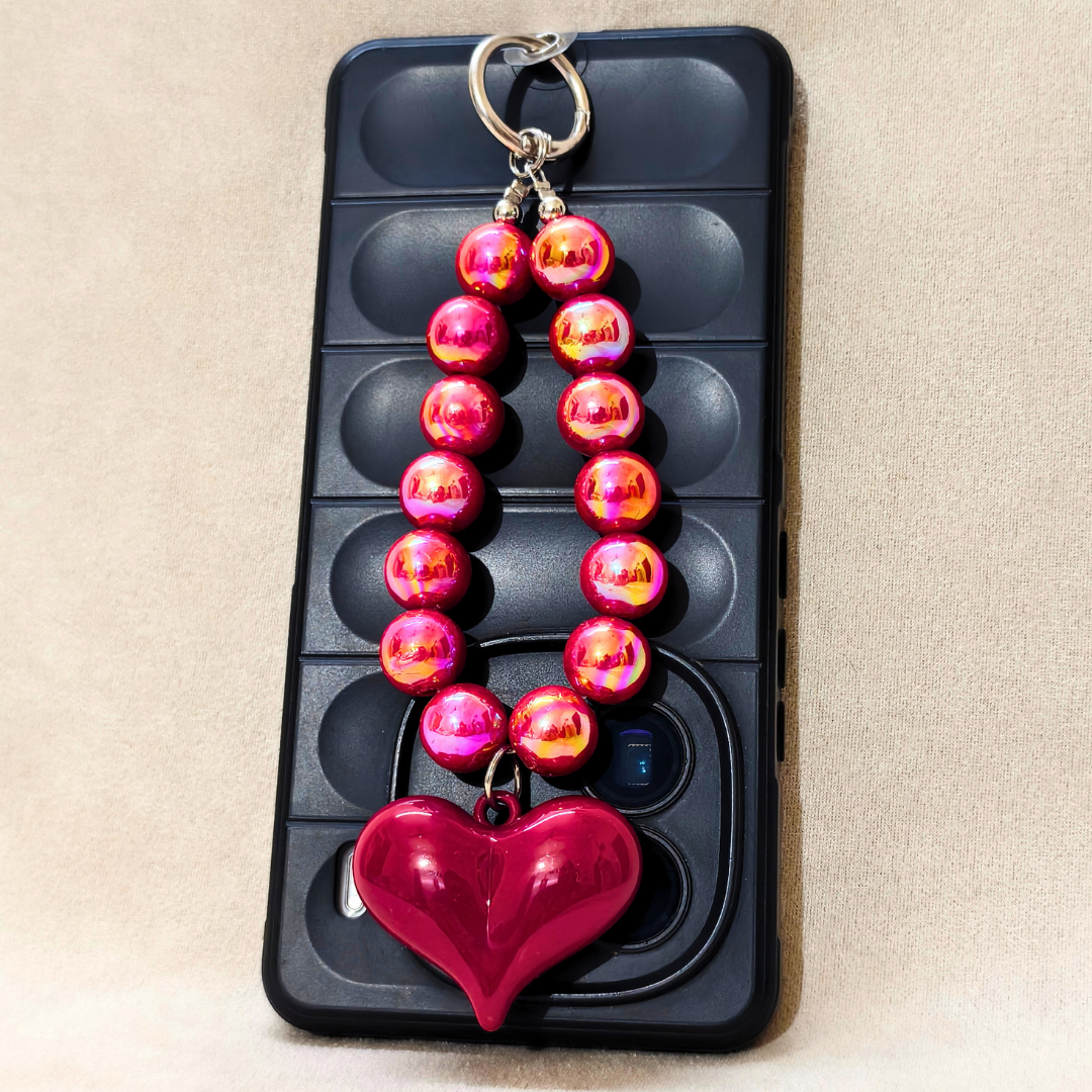 Pink beaded keychain with a heart charm on a black phone case.