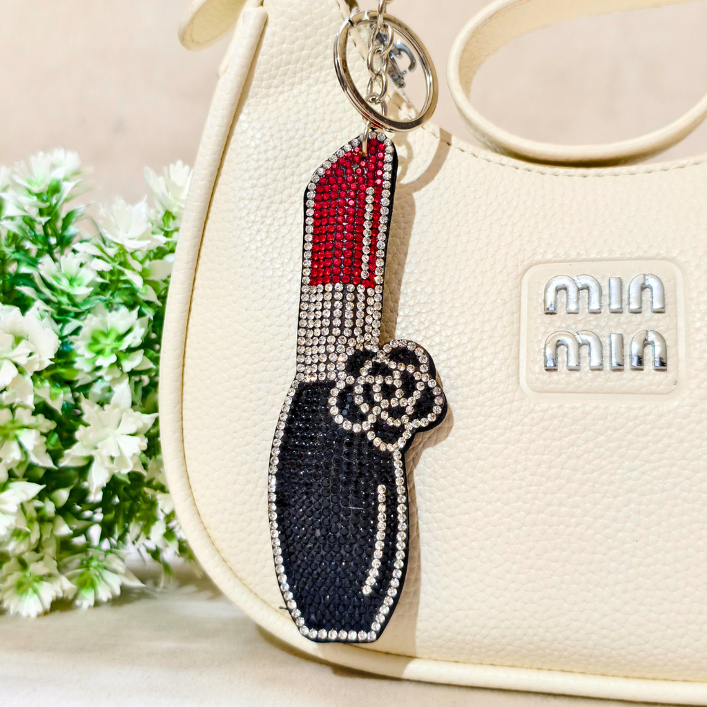 Big Lipstick Bag Charm Attached On Purse In The Font Of Beige Background.