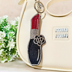 Big Lipstick Bag Charm Attached On Purse In The Font Of Beige Background.