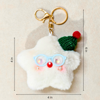 A fluffy white star-shaped keychain charm with light blue glasses, a red nose, and a green knit hat with a red pom-pom, shown on a beige background with black dimension lines and text indicating 4 in by 6 in measurements.