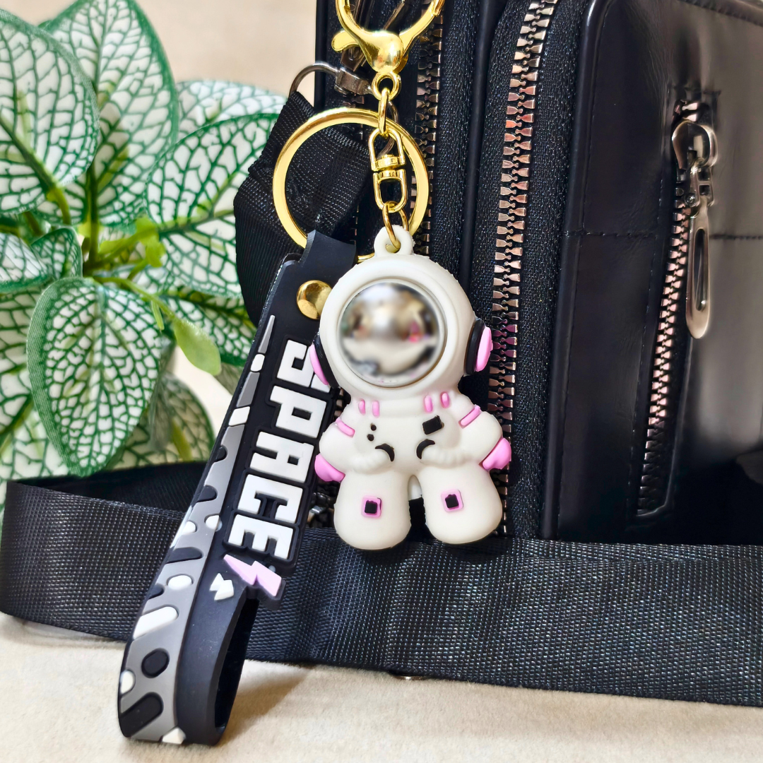 Small Astronaut Keyring Attached With Purse As Bag Charm On Beige Background.