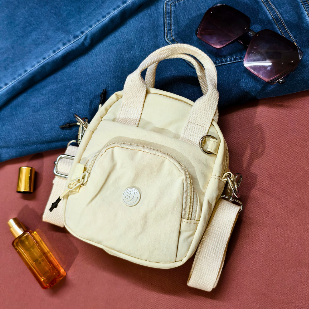 Beige handbag with sunglasses and a bottle on a red surface