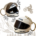 Two small motorcycle helmet keychains shown on a white background with decorative line drawings of mountains, trees, and a motorcycle silhouette. The keychains are cream/off-white with black visors and black printed text reading 'KMD' and 'HELMET'; one also has 'T3MID' visible on the forehead area.