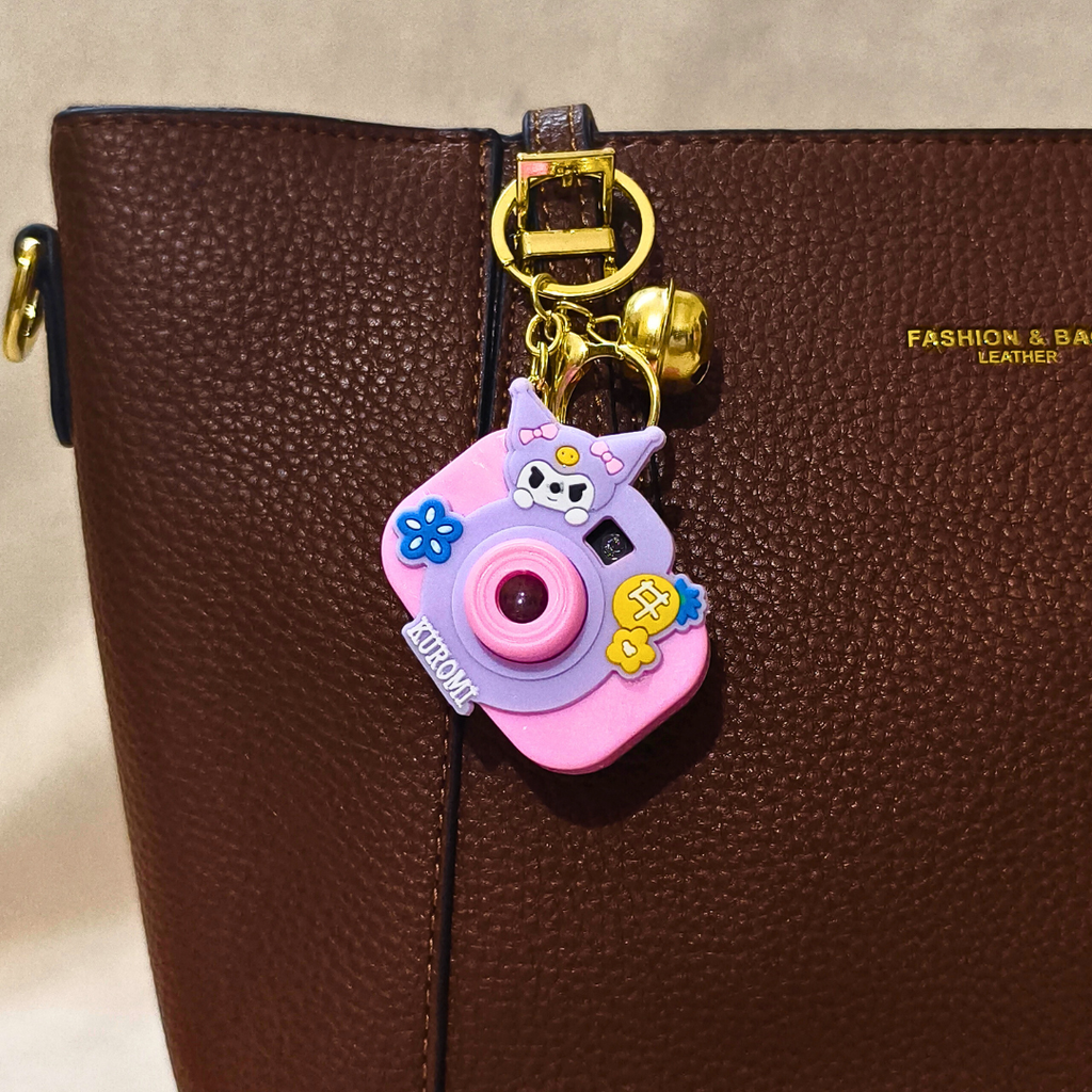 Pink camera-shaped keychain on a brown leather bag