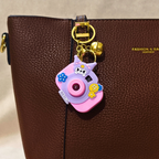 Pink camera-shaped keychain on a brown leather bag