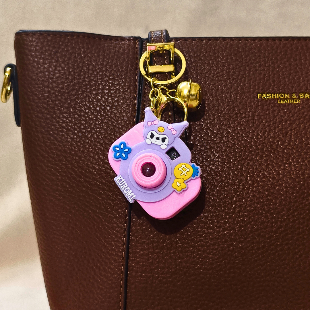 Pink camera-shaped keychain on a brown leather bag