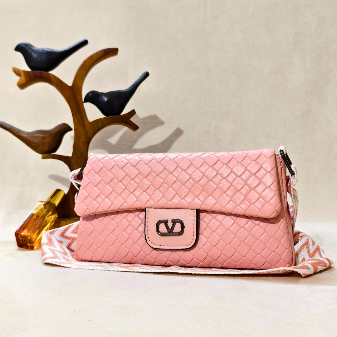 Pink quilted handbag on a beige surface with decorative birds in the background