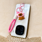 Phone case with a cute bear keychain on a beige surface