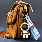 Brown leather handbag with colorful keychain on a dark background