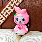 Pink cartoon character figurine on an open book with a brown textured background