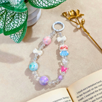 Colorful beaded bracelet with cartoon character charm on a textured surface with leaves and book corner.