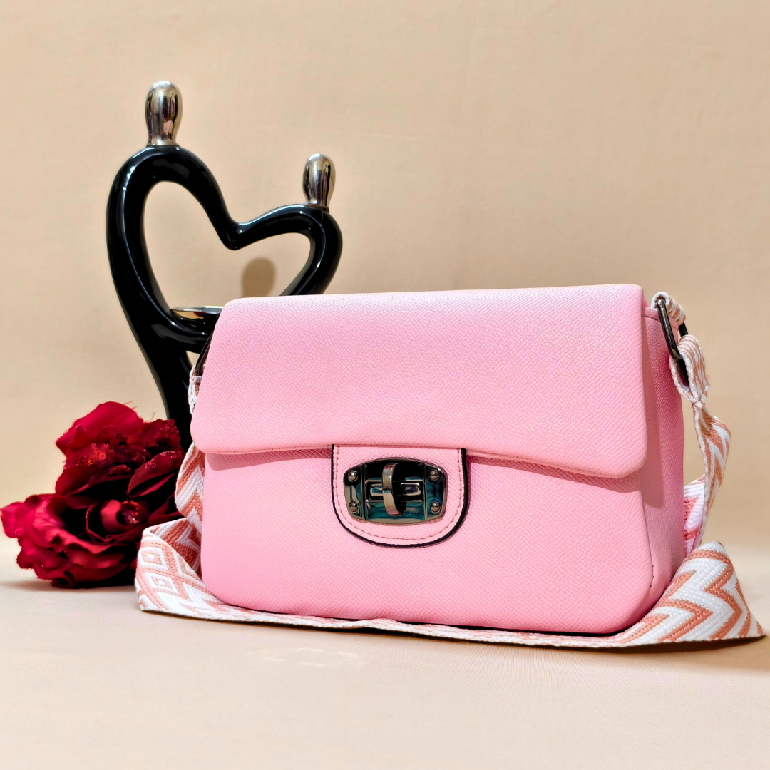 Pink handbag with a red flower and black heart-shaped object on a beige background