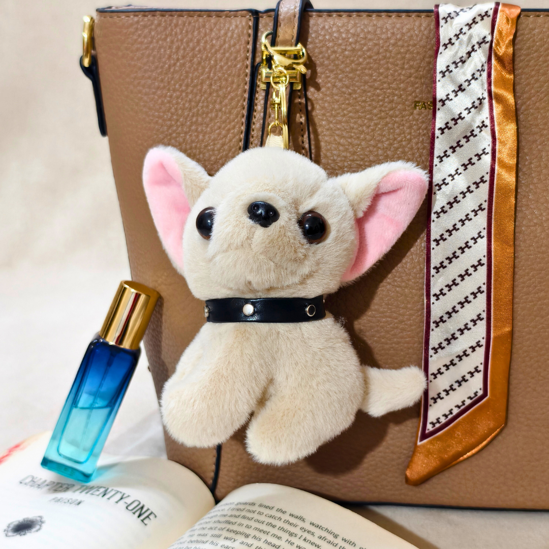 Plush dog toy with a blue perfume bottle on a brown handbag with a patterned strap.