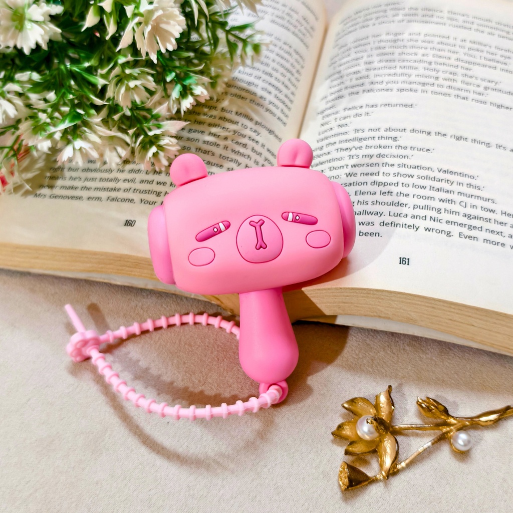 Pink cartoon-style phone with a lanyard on an open book with flowers and a gold leaf decoration.