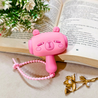 Pink cartoon-style phone with a lanyard on an open book with flowers and a gold leaf decoration.