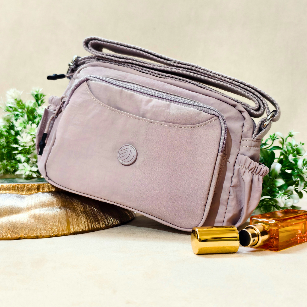 Lavender Lilac Sling Bag With Props In Front Of Beige Background.