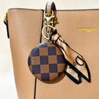 
Round Brown Check Pocket Mirror Attached With Purse As  Bag Charm On  Beige Background.