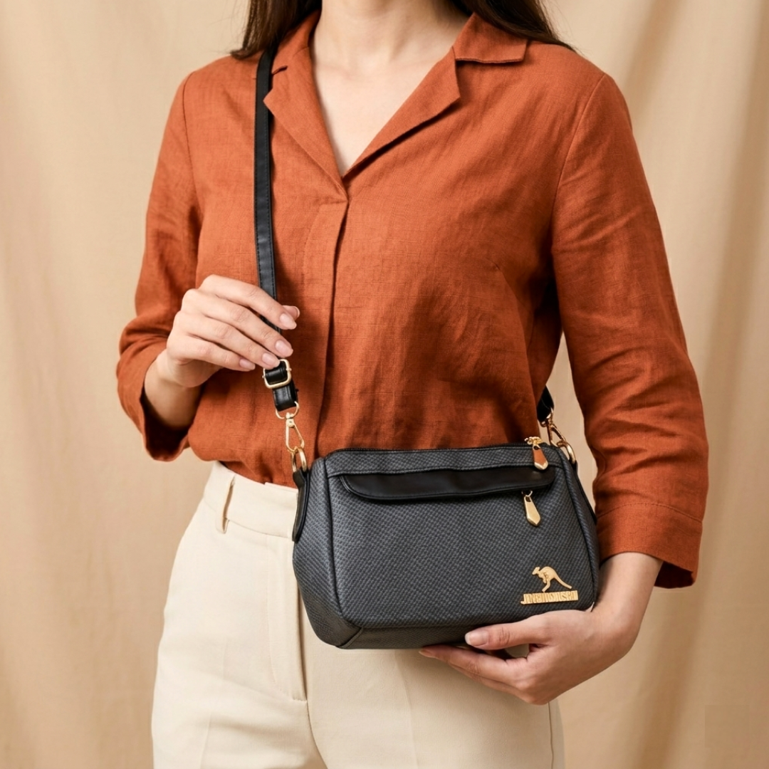 Person holding a black handbag with a visible brand logo against a beige background
