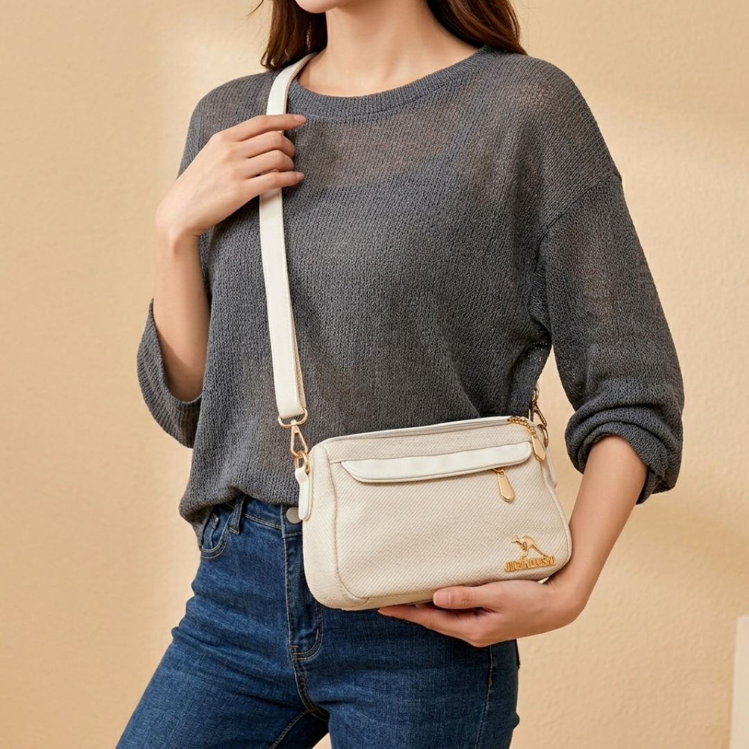 Person holding a beige crossbody bag against a beige background