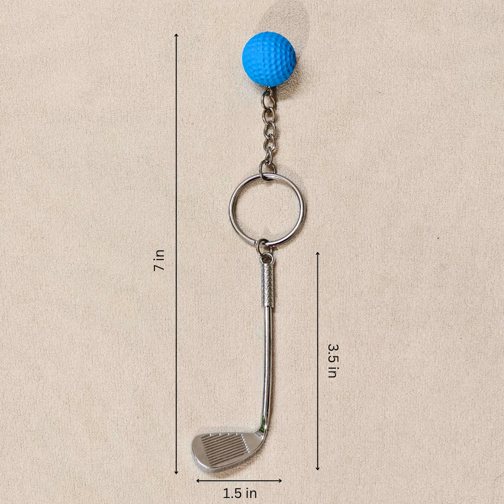 A golf club keychain with a blue golf ball on a chain and a silver metal iron head, shown on a beige textured background with dimension lines indicating 7 in height, 3.5 in shaft length, and 1.